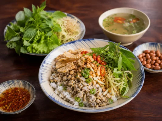 Cơm hến de Hué avec riz, palourdes, herbes, cacahuètes et porc croustillant
