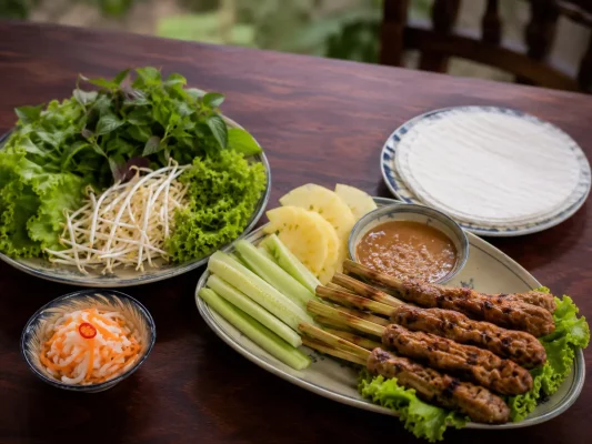 Brochettes de nem lụi de Hué avec herbes fraîches, galettes de riz et sauce