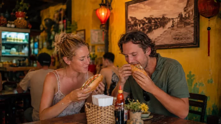 Touristes mangeant un bánh mì à Hội An