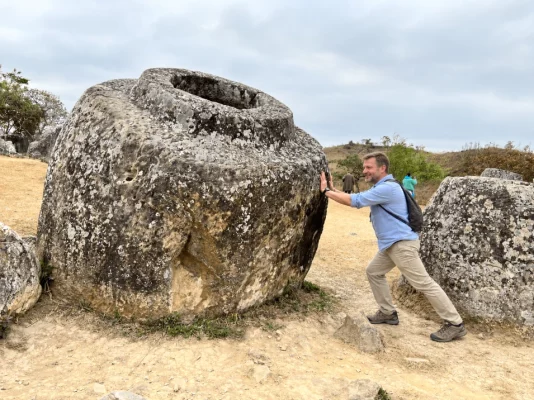 Voyageur devant une jarre monumentale de la plaine des Jarres au Laos